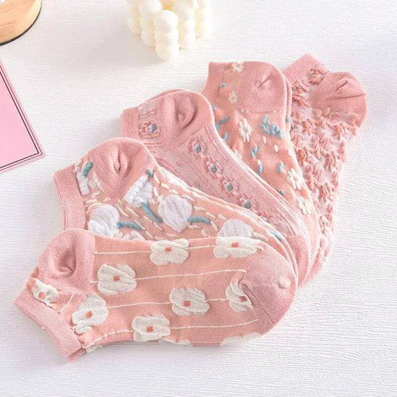 Cinco calcetines rosas con diseño floral 3D, colocados sobre fondo blanco