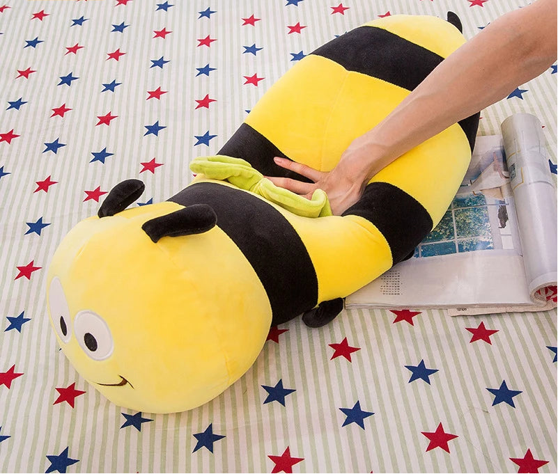 Mano presionando el centro de un peluche de abeja alargado sobre una revista para mostrar su textura suave