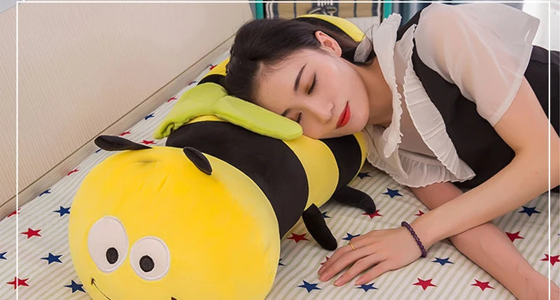 Mujer recostada usando un peluche de abeja kawaii alargado como almohada sobre fondo de estrellas y rayas