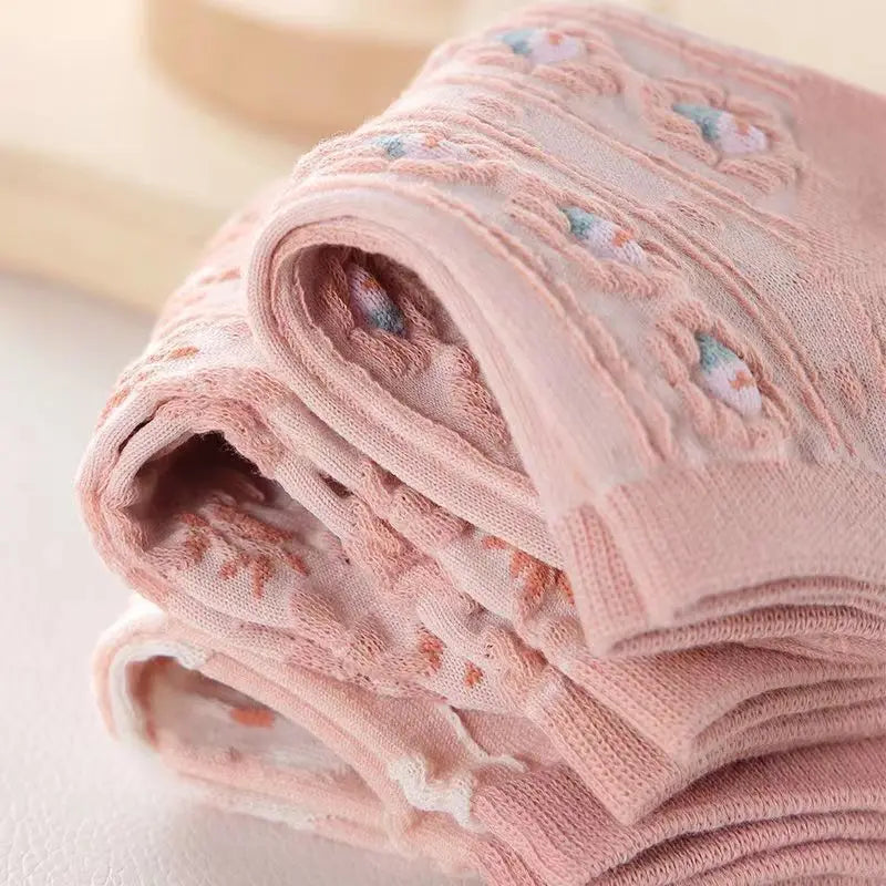 Varios pares de calcetines con flores doblados y apilados, mostrando el detalle del tejido