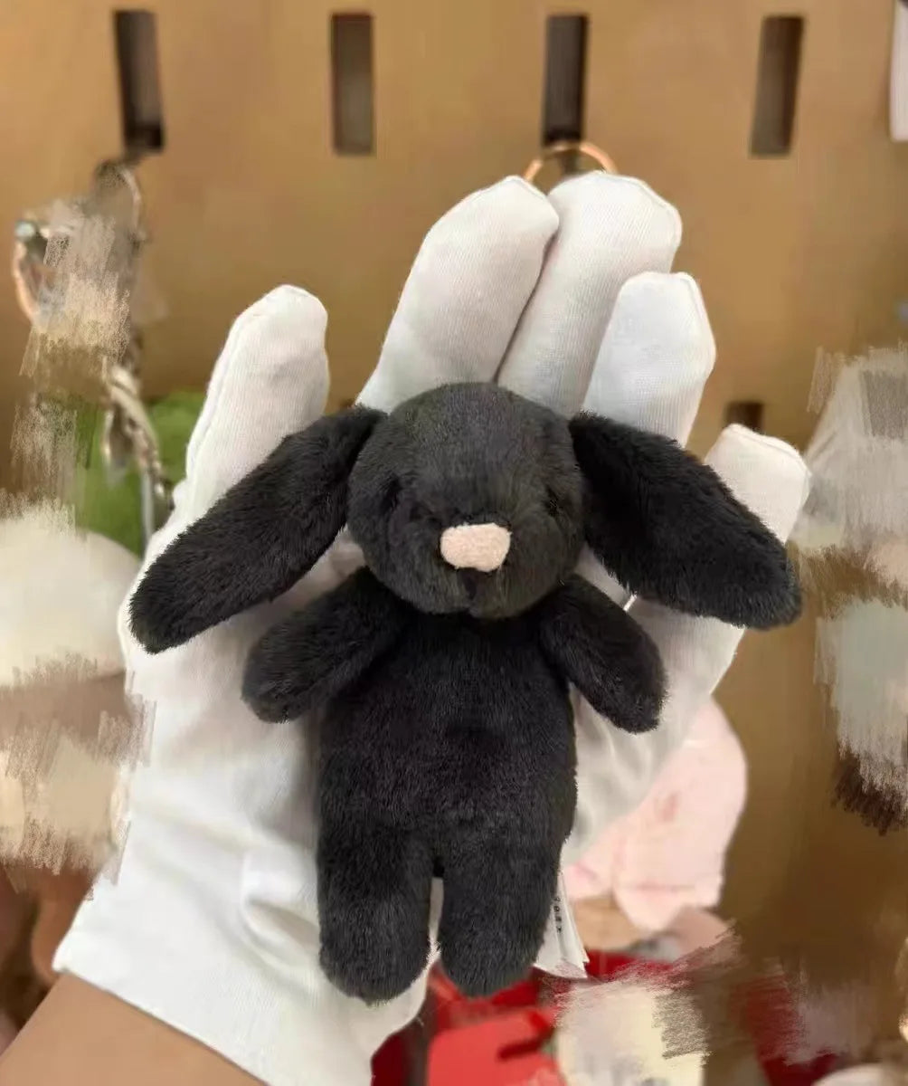 Llavero conejito negro sostenido con guante blanco
