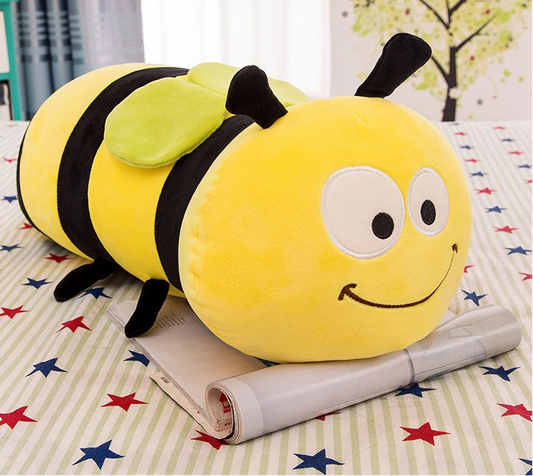 Peluche de abeja kawaii alargado colocado sobre una revista en una mesa con mantel de estrellas y rayas, vista frontal